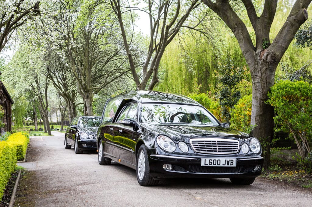 JW Binks hearse and limousine on a tree-lined driveway, Morley